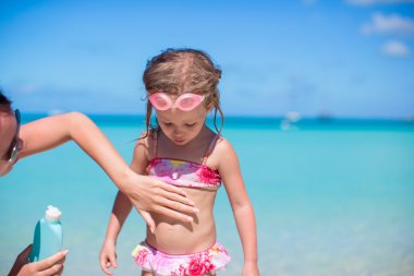 genç anne kızının mide üzerinde uygulanan güneş kremi krem