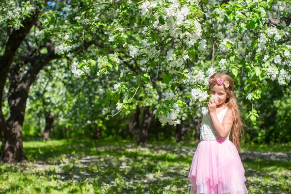 Adorable niña en floreciente huerto de manzanas en un día soleado —  Fotos de Stock