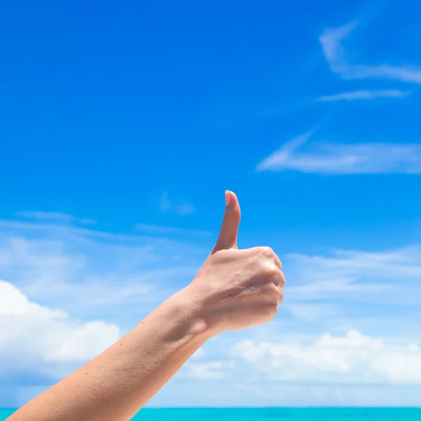 Nahaufnahme Daumen hoch am Strand Hintergrund blauer Himmel — Stockfoto