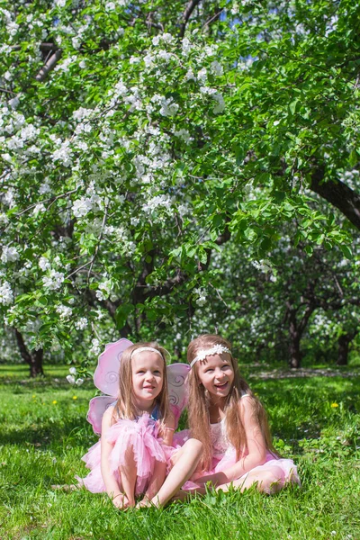 Маленькі дівчата з крилами метеликів у квітучому яблучному саду — стокове фото