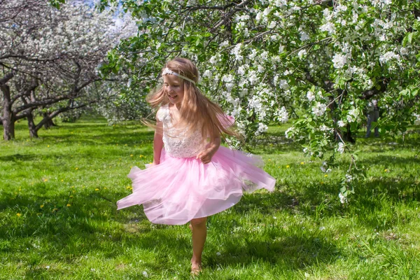 Adorável menina se divertir no pomar de maçã florescente — Fotografia de Stock