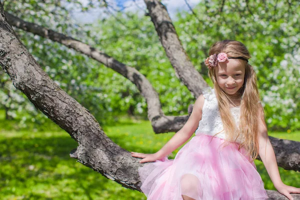 Portret van klein schattig meisje, zittend op bloeiende appelboom — Stockfoto