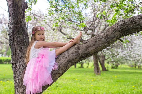 Liten bedårande flicka sitter på blommande äppelträd — Stockfoto