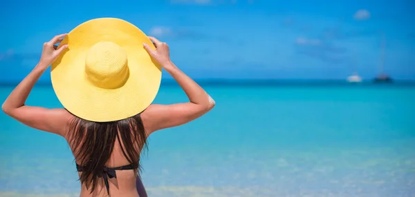 Woman sitting in yellow hat on white sand beach enjoying summer vacation — Stock Photo, Image