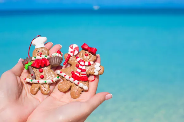 ターコイズ ブルーの海に対する手のジンジャーブレッド クッキーをクリスマスのクローズ アップ — ストック写真