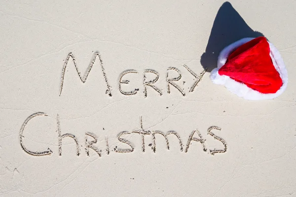 Vrolijk kerstfeest geschreven op tropisch strand wit zand met xmas hoed — Stockfoto