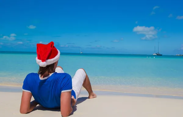 Vista posteriore del giovane uomo in cappello di Babbo Natale sulla spiaggia tropicale — Foto Stock