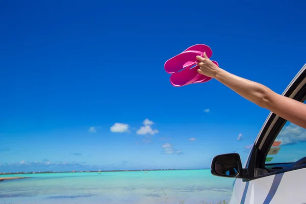 Chanclas desde la ventana de un coche en la playa tropical de fondo —  Fotos de Stock