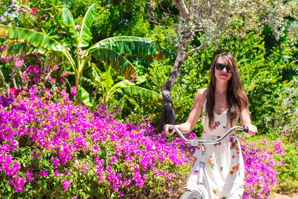 Young woman riding a bike on tropical resort at beautiful garden — Stock Photo, Image