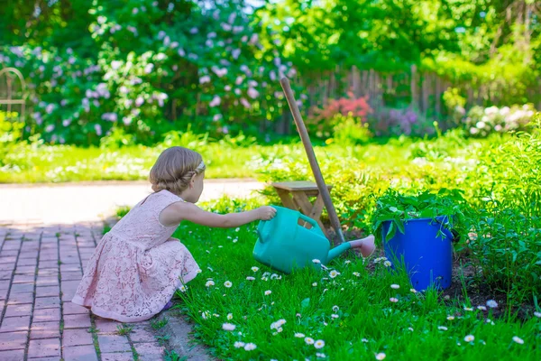 Adorable cute girl with a watering can at big green garden — Stock Photo, Image