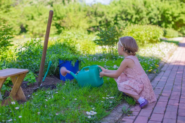 Little adorable girl water flowers with a watering can in park — Stock Photo, Image