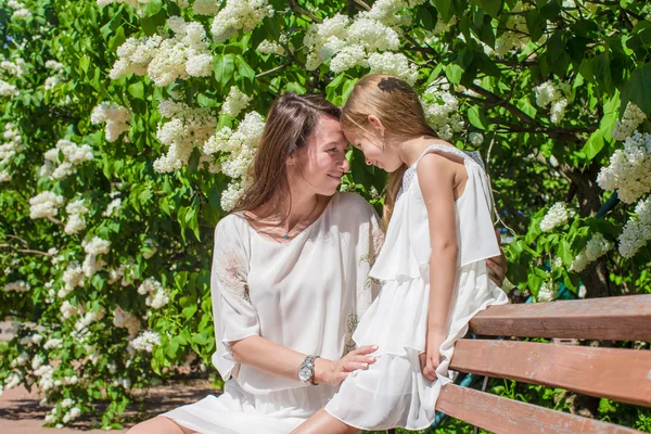 Happy mother and adorable girl enjoying warm day in lush garden — Stock Photo, Image