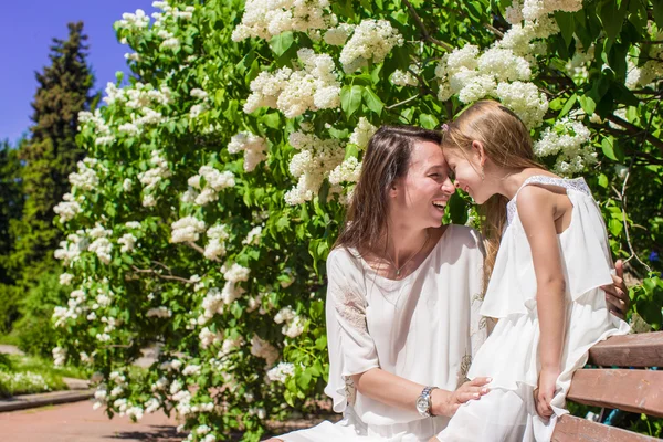 Happy mother and adorable girl enjoy spring day in lush garden — Stock Photo, Image
