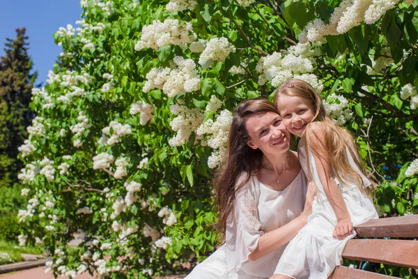 Happy mother and adorable girl enjoying warm day in lush garden — Stock Photo, Image