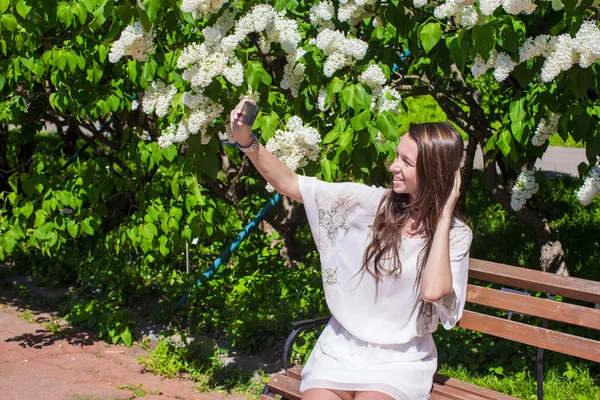 Young woman take photo on her phone at blossoming lilac garden — Stock Photo, Image