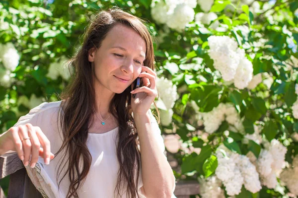 Jovem mulher falando em seu telefone no jardim de flores — Fotografia de Stock