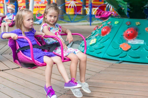 Deux petites sœurs mignonnes montent sur le carrousel dans le parc — Photo