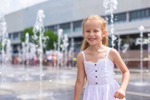 Liten glad tjej ha roligt i gatan fontän på varm solig dag — Stockfoto