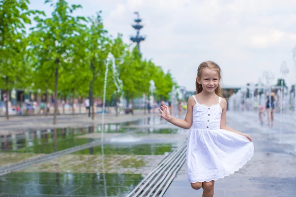 Kleines glückliches Mädchen hat Spaß im Straßenbrunnen an einem heißen, sonnigen Tag — Stockfoto