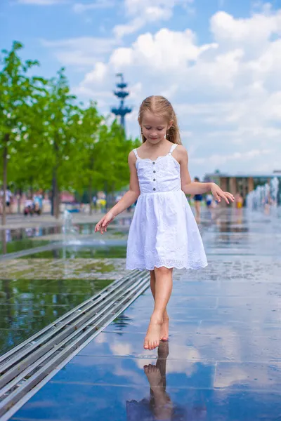 Niña linda caminando en la fuente de la calle abierta en el día soleado caliente —  Fotos de Stock