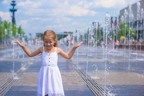 Kleines glückliches Mädchen hat Spaß im Straßenbrunnen an einem heißen, sonnigen Tag — Stockfoto