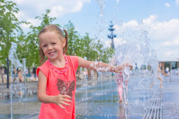 Niña adorable divertirse en la fuente de la calle en el día soleado caliente —  Fotos de Stock