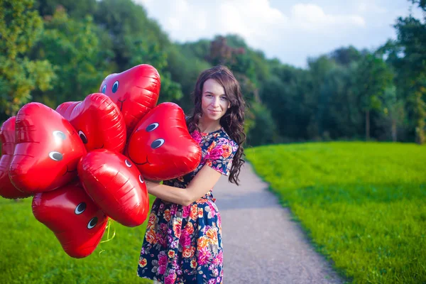 Giovane donna attraente felice in bel vestito con palloncini rossi a piedi fuori — Foto Stock