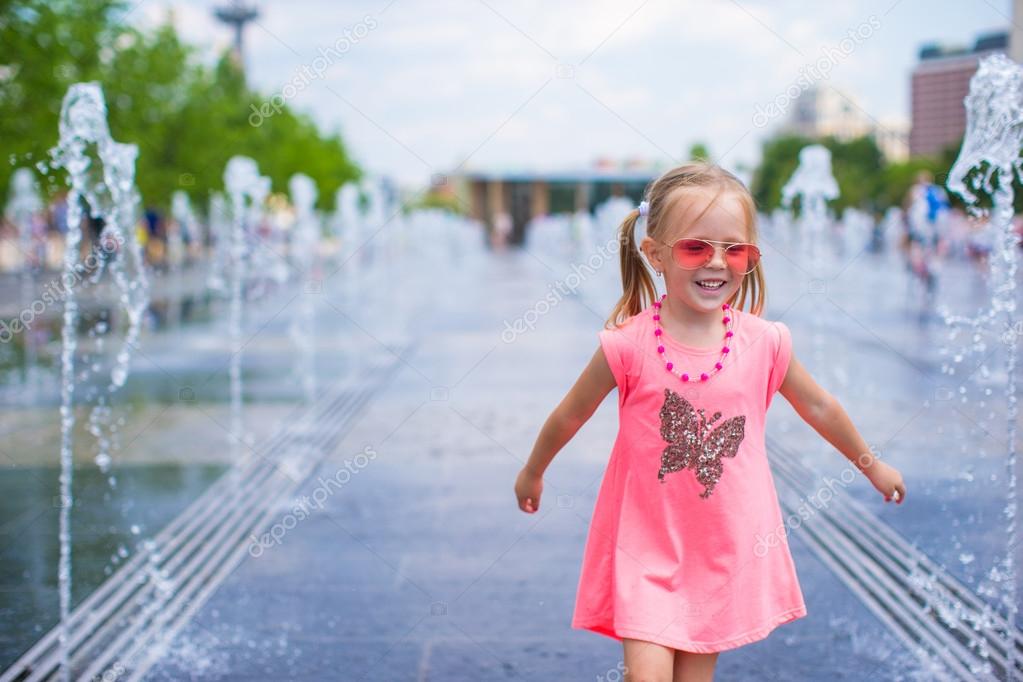 Little adorable girl have fun in street fountain