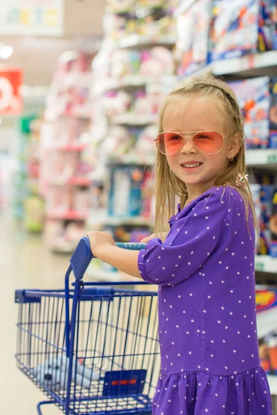Malá módní dívka s vozíkem ve velké nákupní centrum — Stock fotografie