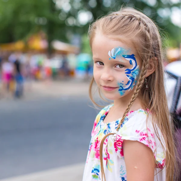 Kleines süßes Mädchen mit einem Muster auf dem Gesicht im Freien — Stockfoto
