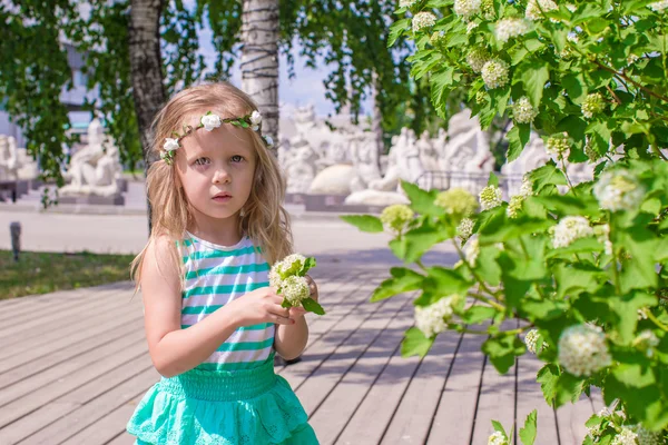 Pequena menina bonita perto de flores brancas no jardim — Fotografia de Stock