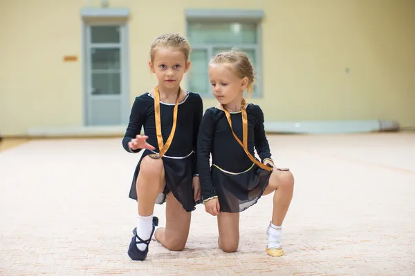 Two little gymnasts in the gym with medals — Stock Photo, Image