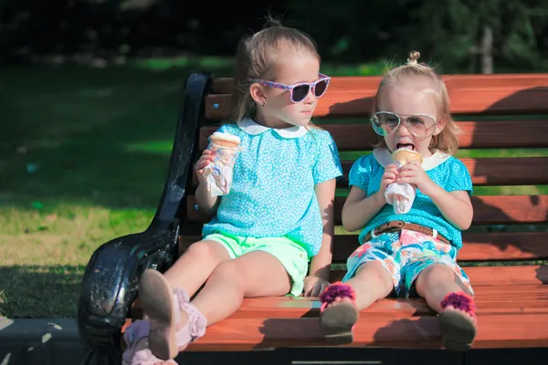 Две маленькие очаровательные сестры едят мороженое на открытом воздухе — стоковое фото