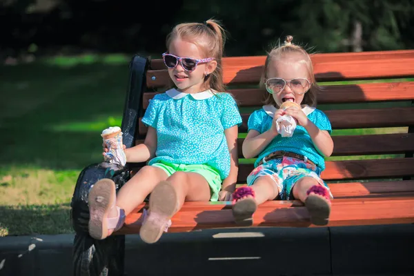 Zwei kleine entzückende Mädchen, die draußen Eis essen — Stockfoto