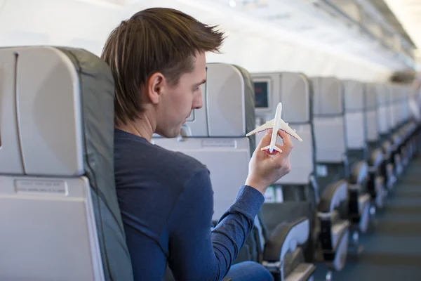 Happy man with small model airplane inside a large aircraft — Stock Photo, Image