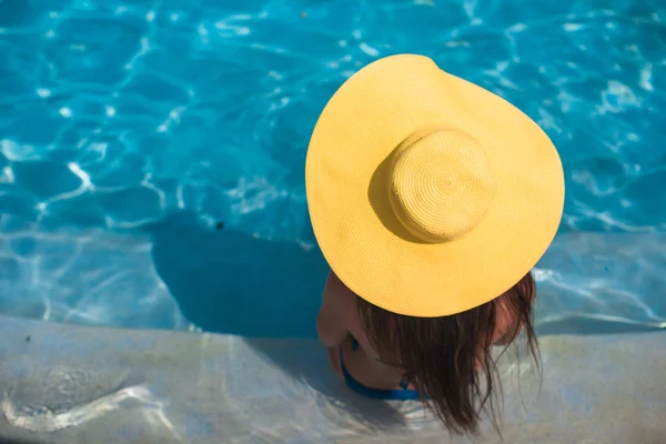 Young woman in yellow hat relaxing at swimming pool — Stock Photo, Image