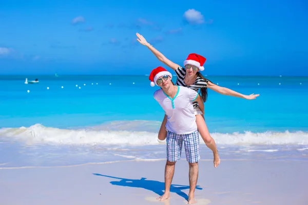 Felice coppia indossa cappello di Babbo Natale divertirsi alla spiaggia di caraibi — Foto Stock