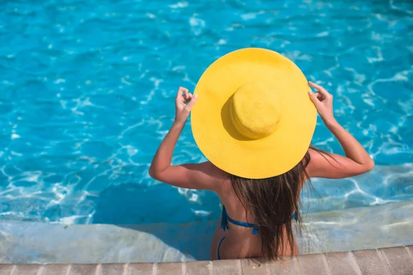 Vrouw in geel hoed ontspannen bij het zwembad — Stockfoto