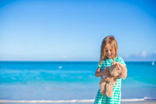 Urocze dziewczynki z jej królik zabawki na wakacje na tropikalnej plaży — Zdjęcie stockowe