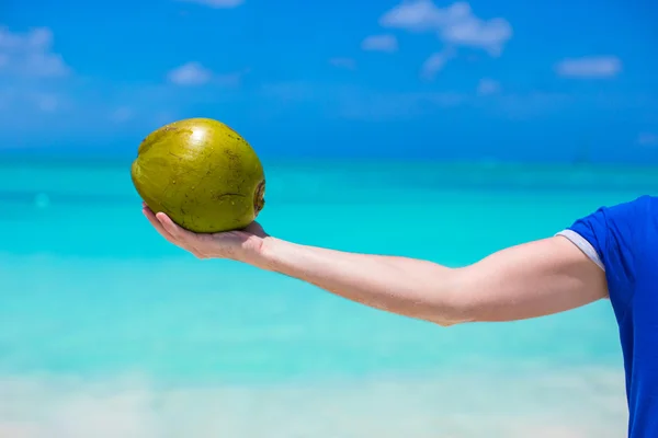 Gros plan de noix de coco dans les mains hmale fond de la mer turquoise — Photo
