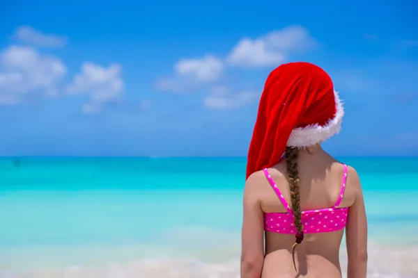 Rozkošná holčička v červeném klobouku santa Užijte si dovolenou na pláži — Stock fotografie