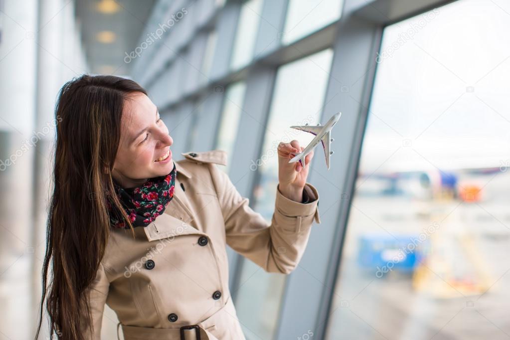 Happy woman with small model airplane inside airport