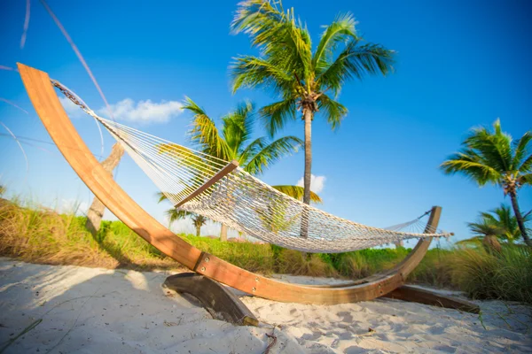 Halm hängmatta i skuggan av palmerna på tropisk strand vid havet — Stockfoto