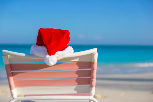 Feche o chapéu de Santa na cadeira longue na praia tropical — Fotografia de Stock