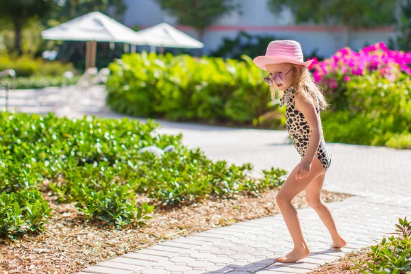 Adorable little girl at hat and swmsuit in exotic resort — Stock Photo, Image