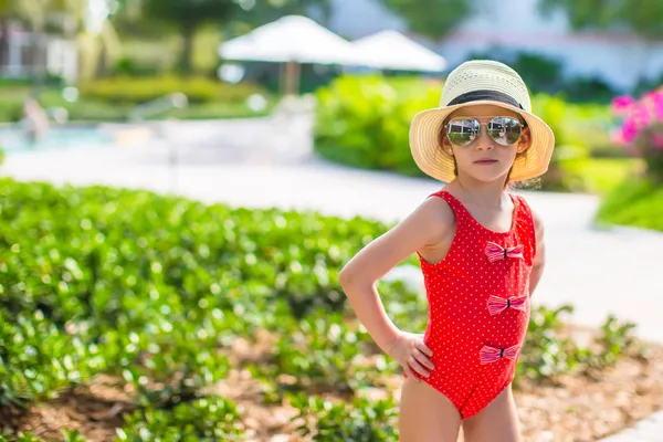 Adorable little girl at hat and swmsuit in exotic resort — Stock Photo, Image