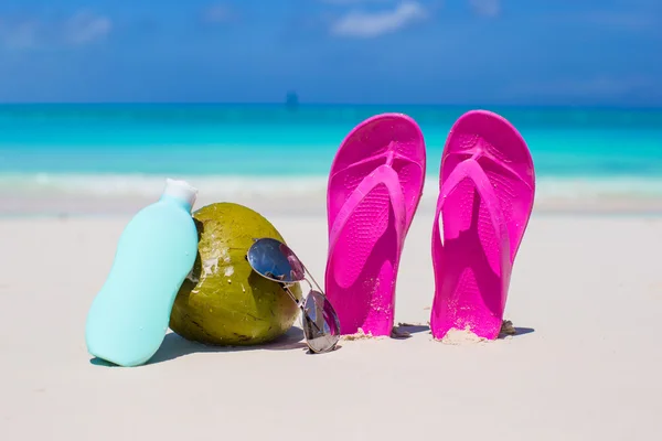 Tongs, noix de coco et crème solaire sur sable blanc — Photo
