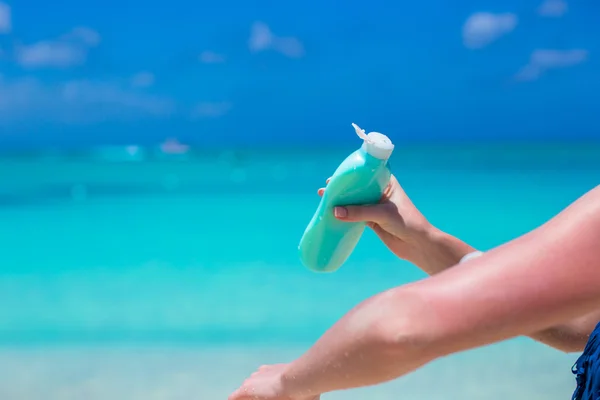 Mujer mano poniendo protector solar de una botella de crema solar — Foto de Stock