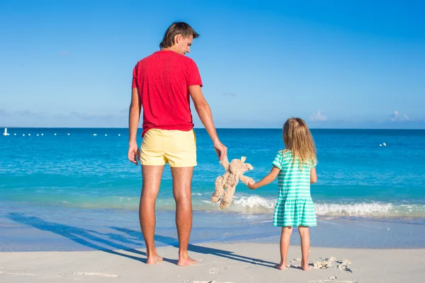 Giovane padre con bambina che tiene un coniglio peluche sulla spiaggia esotica — Foto Stock