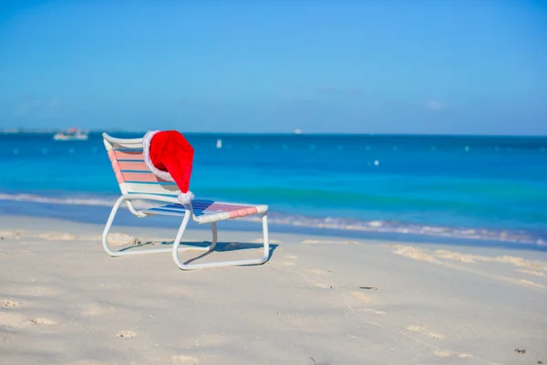 特写圣诞老人的帽子在椅子上贵妃在地处热带的海滩上 — 图库照片